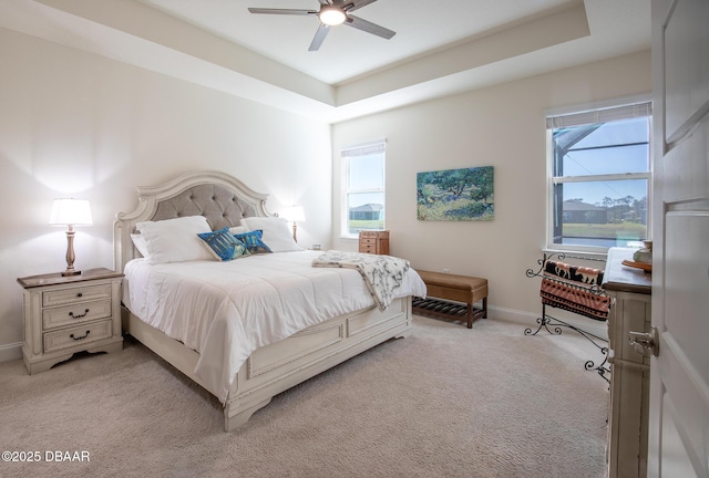 bedroom featuring ceiling fan, a raised ceiling, and light colored carpet