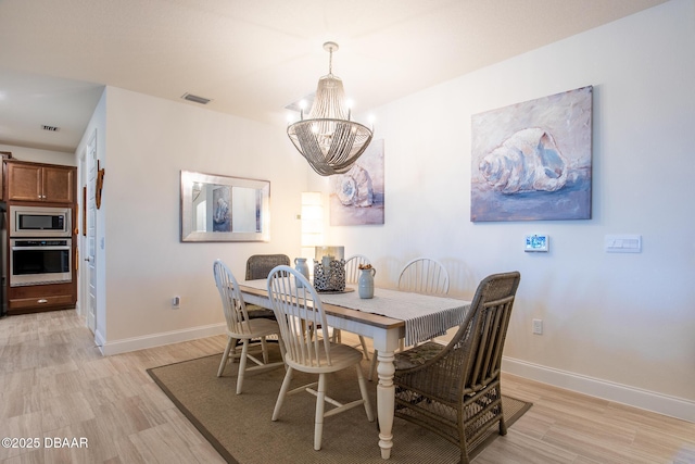 dining space featuring light hardwood / wood-style flooring and a chandelier