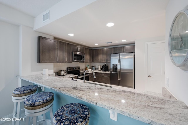 3721 S Atlantic Ave Unit 1101, Daytona Beach Shores, FL 32118 - kitchen with appliances with stainless steel finishes, dark brown cabinets, light stone counters, a breakfast bar area, and recessed lighting