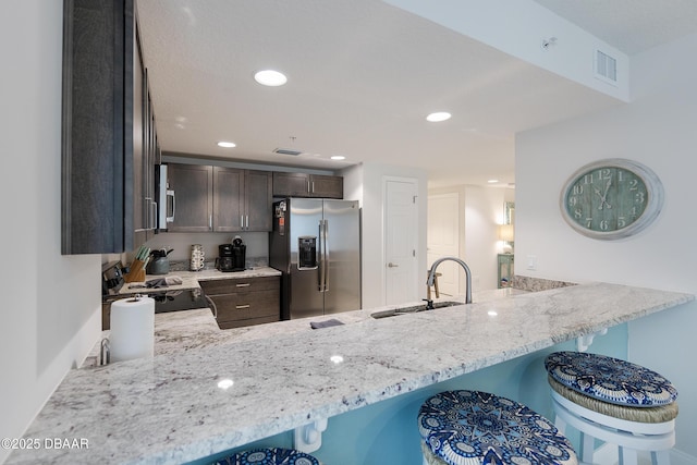 3721 S Atlantic Ave Unit 1101, Daytona Beach Shores, FL 32118 - kitchen featuring stainless steel fridge, stove, a peninsula, light stone countertops, and dark brown cabinets