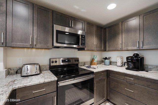 3721 S Atlantic Ave Unit 1101, Daytona Beach Shores, FL 32118 - kitchen with stainless steel appliances, dark brown cabinetry, and light stone counters