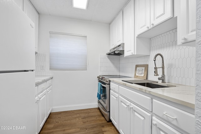 kitchen featuring electric range, white fridge, white cabinetry, and backsplash