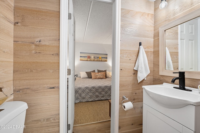 bathroom with wooden walls, vanity, and toilet