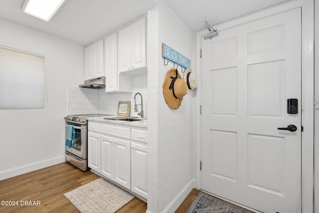 kitchen with white cabinetry, electric range, sink, light hardwood / wood-style floors, and decorative backsplash