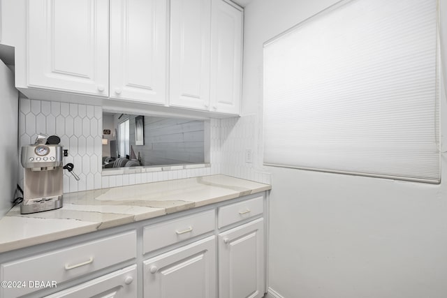 interior space with white cabinets, backsplash, and light stone countertops