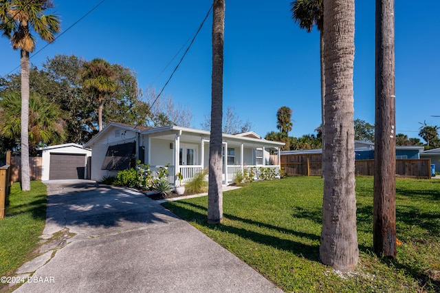 single story home featuring a porch, an outbuilding, a front yard, and a garage