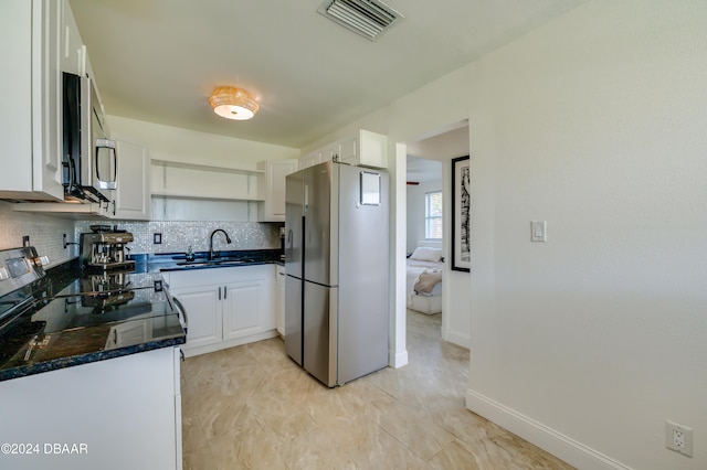 kitchen featuring sink, backsplash, dark stone counters, white cabinets, and appliances with stainless steel finishes