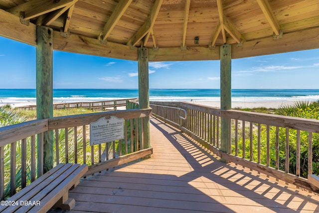 wooden deck featuring a gazebo, a water view, and a beach view