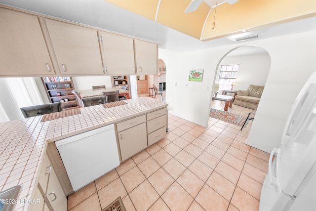 kitchen featuring white appliances, cream cabinets, ceiling fan, light tile patterned floors, and tile counters