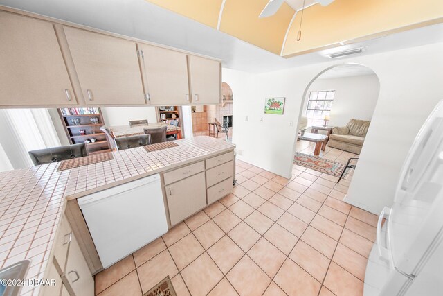 110 Ponce Terrace Cir, Ponce Inlet, FL 32127 - kitchen featuring arched walkways, white appliances, tile counters, light tile patterned floors, and a ceiling fan