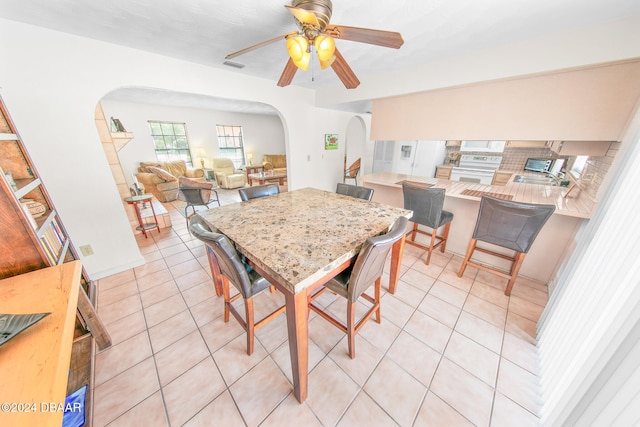 dining room with light tile patterned floors, ceiling fan, and sink