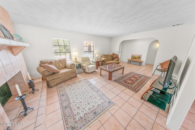 110 Ponce Terrace Cir, Ponce Inlet, FL 32127 - living room with arched walkways, light tile patterned floors, a brick fireplace, and a textured ceiling
