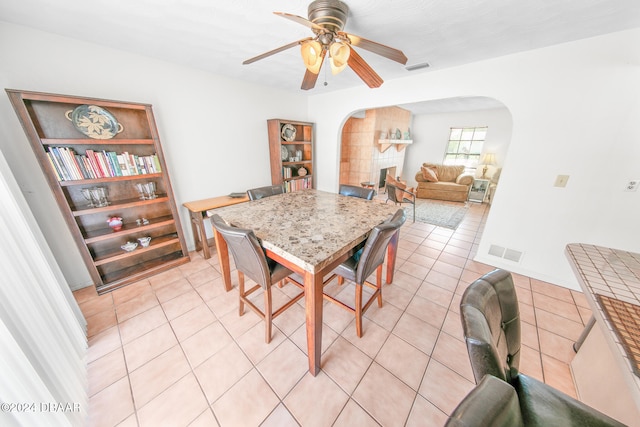 tiled dining space featuring a tiled fireplace and ceiling fan