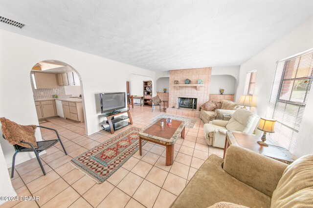 living room featuring a fireplace, light tile patterned floors, and a textured ceiling