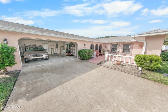110 Ponce Terrace Cir, Ponce Inlet, FL 32127 - ranch-style house featuring an attached garage, concrete driveway, stucco siding, covered porch, and a shingled roof