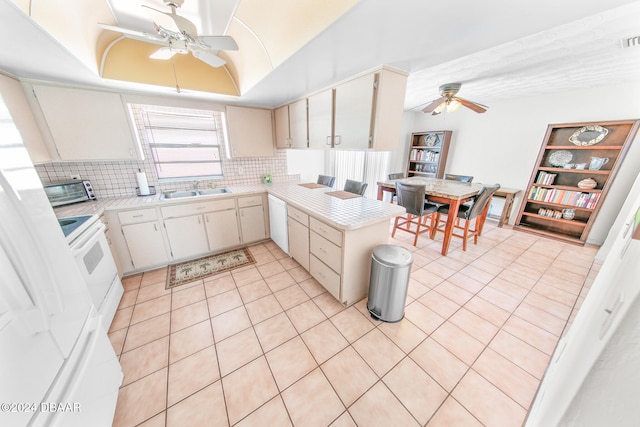 kitchen with kitchen peninsula, backsplash, white appliances, a raised ceiling, and sink