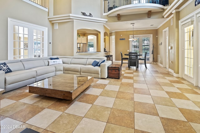 living room featuring ornamental molding, an inviting chandelier, french doors, and a healthy amount of sunlight