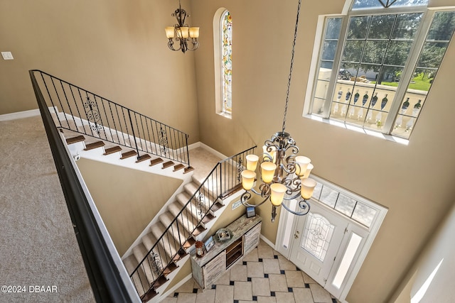 entrance foyer featuring a towering ceiling, light colored carpet, and a chandelier