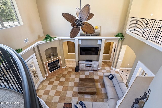 living room with ceiling fan and a towering ceiling