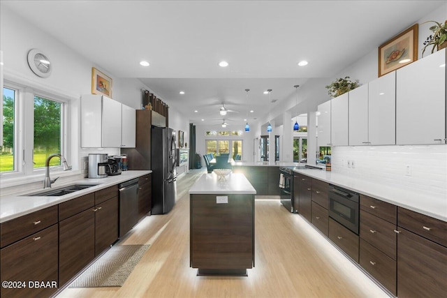 kitchen featuring stainless steel appliances, sink, light hardwood / wood-style flooring, white cabinets, and a kitchen island