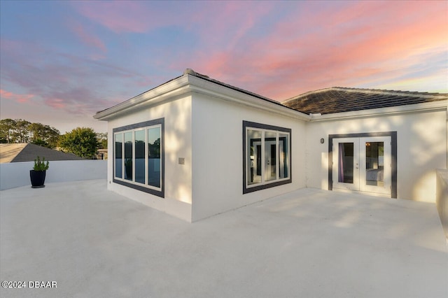 back house at dusk with a patio area and french doors