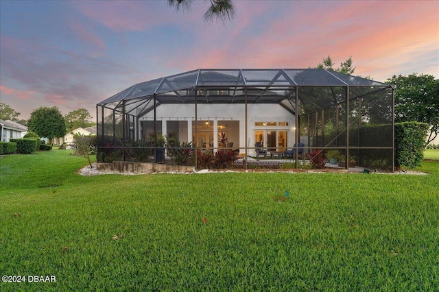 back house at dusk with a lanai and a yard