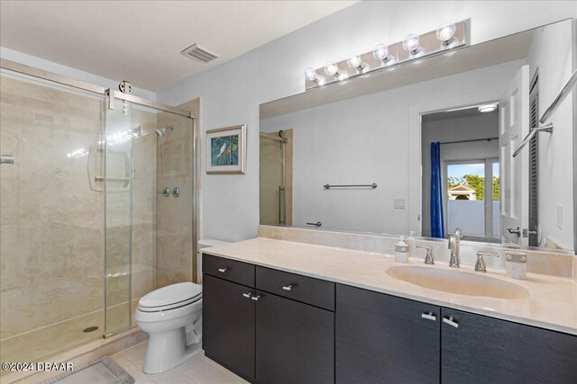 bathroom with toilet, vanity, tile patterned floors, and walk in shower