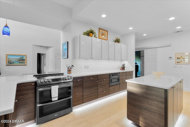 kitchen featuring white cabinets, decorative backsplash, appliances with stainless steel finishes, decorative light fixtures, and light hardwood / wood-style floors