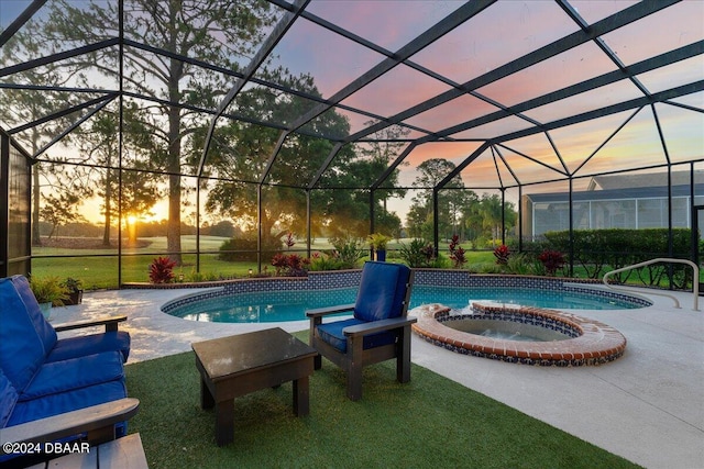 pool at dusk featuring an in ground hot tub, glass enclosure, a patio area, and a lawn