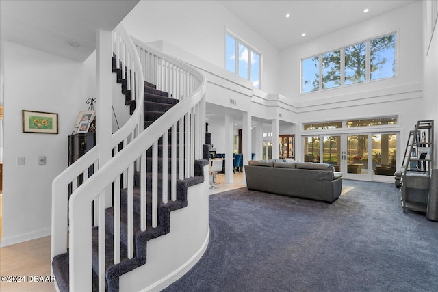 carpeted living room with french doors and a towering ceiling