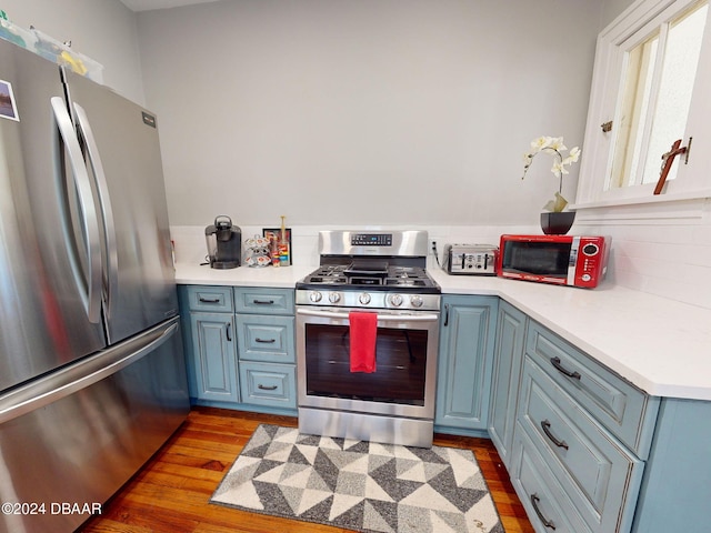 kitchen with blue cabinets, stainless steel appliances, and light hardwood / wood-style flooring