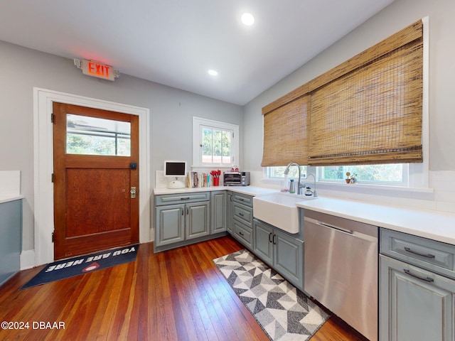 kitchen featuring stainless steel dishwasher, sink, gray cabinetry, and dark wood-type flooring