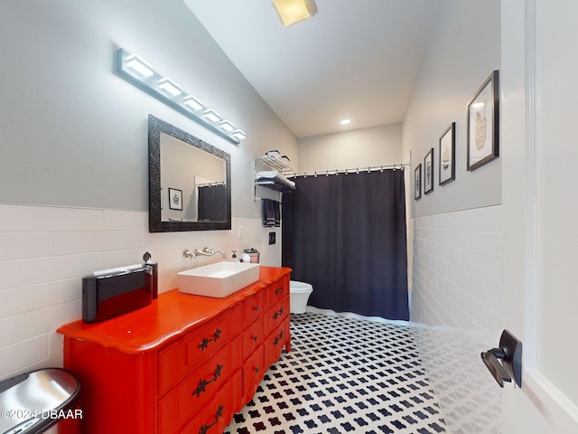 bathroom with a shower with shower curtain, vanity, toilet, and tile walls