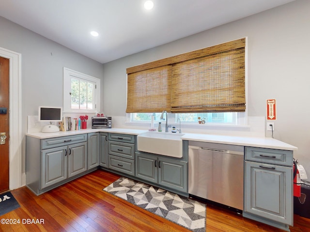 kitchen featuring gray cabinetry, sink, stainless steel dishwasher, and hardwood / wood-style flooring