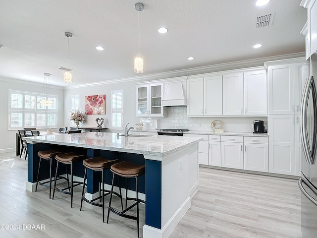 kitchen with a kitchen island with sink, white cabinets, and decorative light fixtures