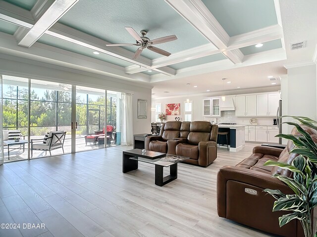 living room with coffered ceiling, ornamental molding, ceiling fan, beam ceiling, and light wood-type flooring