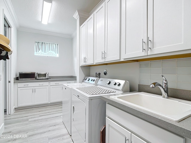 laundry room with light hardwood / wood-style floors, cabinets, sink, washing machine and clothes dryer, and crown molding