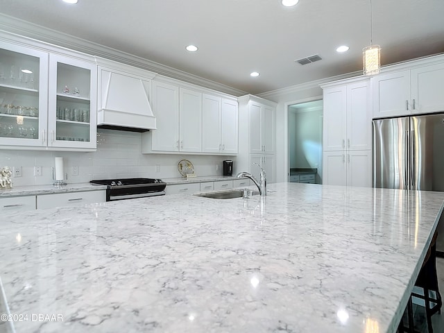 kitchen with hanging light fixtures, stainless steel stove, custom exhaust hood, and white cabinetry