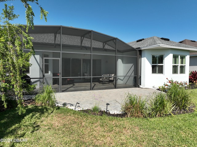 back of property featuring a yard, glass enclosure, and a patio area