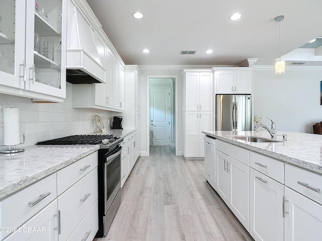 kitchen featuring stainless steel appliances, white cabinetry, sink, light hardwood / wood-style flooring, and pendant lighting