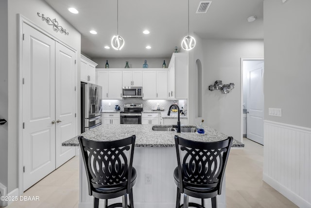 110 Longridge Ln, Ormond Beach, FL 32174 - kitchen featuring stainless steel appliances, a sink, white cabinetry, a breakfast bar area, and light stone countertops