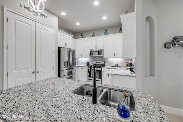 110 Longridge Ln, Ormond Beach, FL 32174 - kitchen featuring appliances with stainless steel finishes, recessed lighting, white cabinetry, tasteful backsplash, and light stone counters