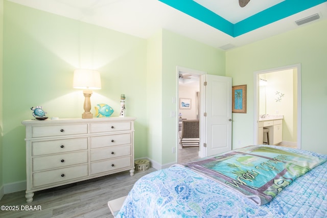 bedroom with light wood-type flooring and ensuite bathroom