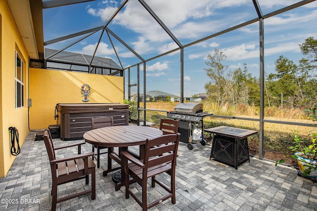 view of patio with grilling area, a hot tub, and glass enclosure