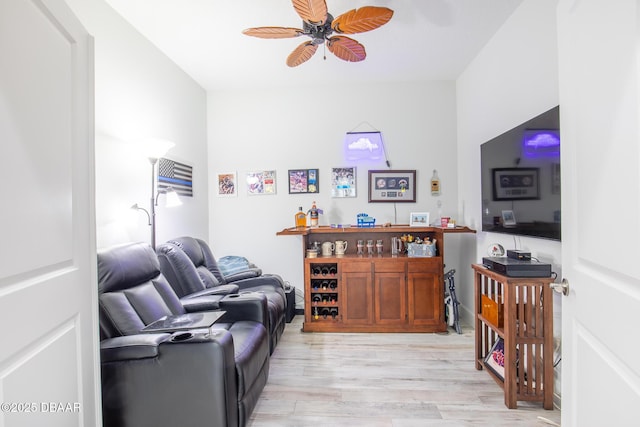 living room with light hardwood / wood-style floors, ceiling fan, and bar area