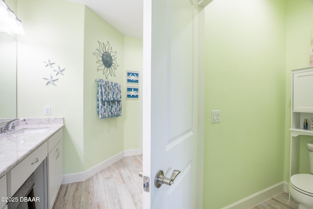 bathroom with hardwood / wood-style flooring, vanity, and toilet