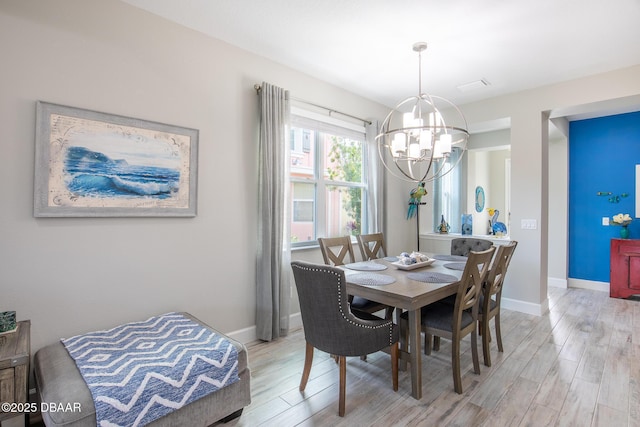 dining space featuring an inviting chandelier and light wood-type flooring