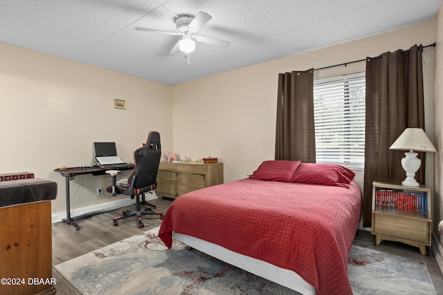 bedroom with ceiling fan, wood-type flooring, and a textured ceiling