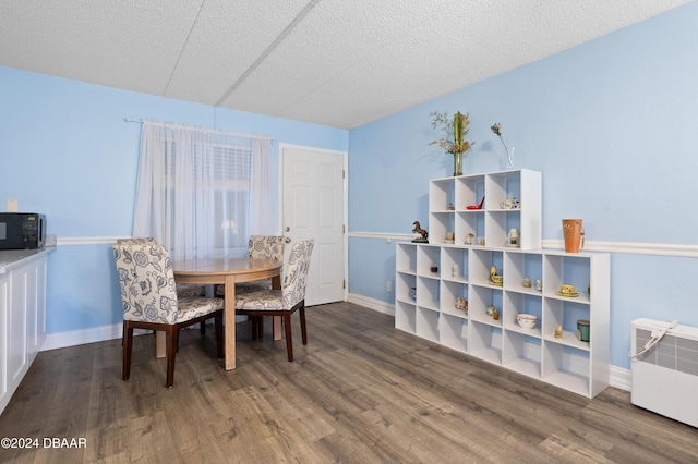 dining space featuring heating unit, radiator heating unit, dark hardwood / wood-style floors, and a textured ceiling