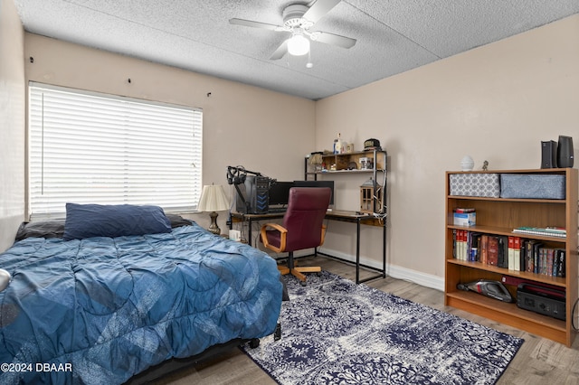 bedroom with wood-type flooring, a textured ceiling, and ceiling fan